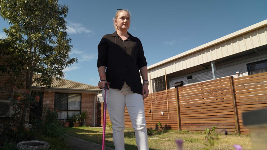 Mandy Hunwick stands in her backyard with a cane.