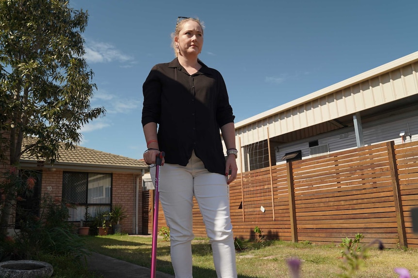 Mandy Hunwick stands in her backyard with a cane.