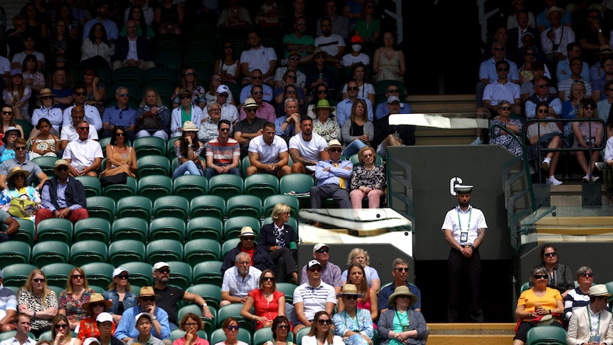 Rows of empty seats are seen among the crowd at Wimbledon stadium. 