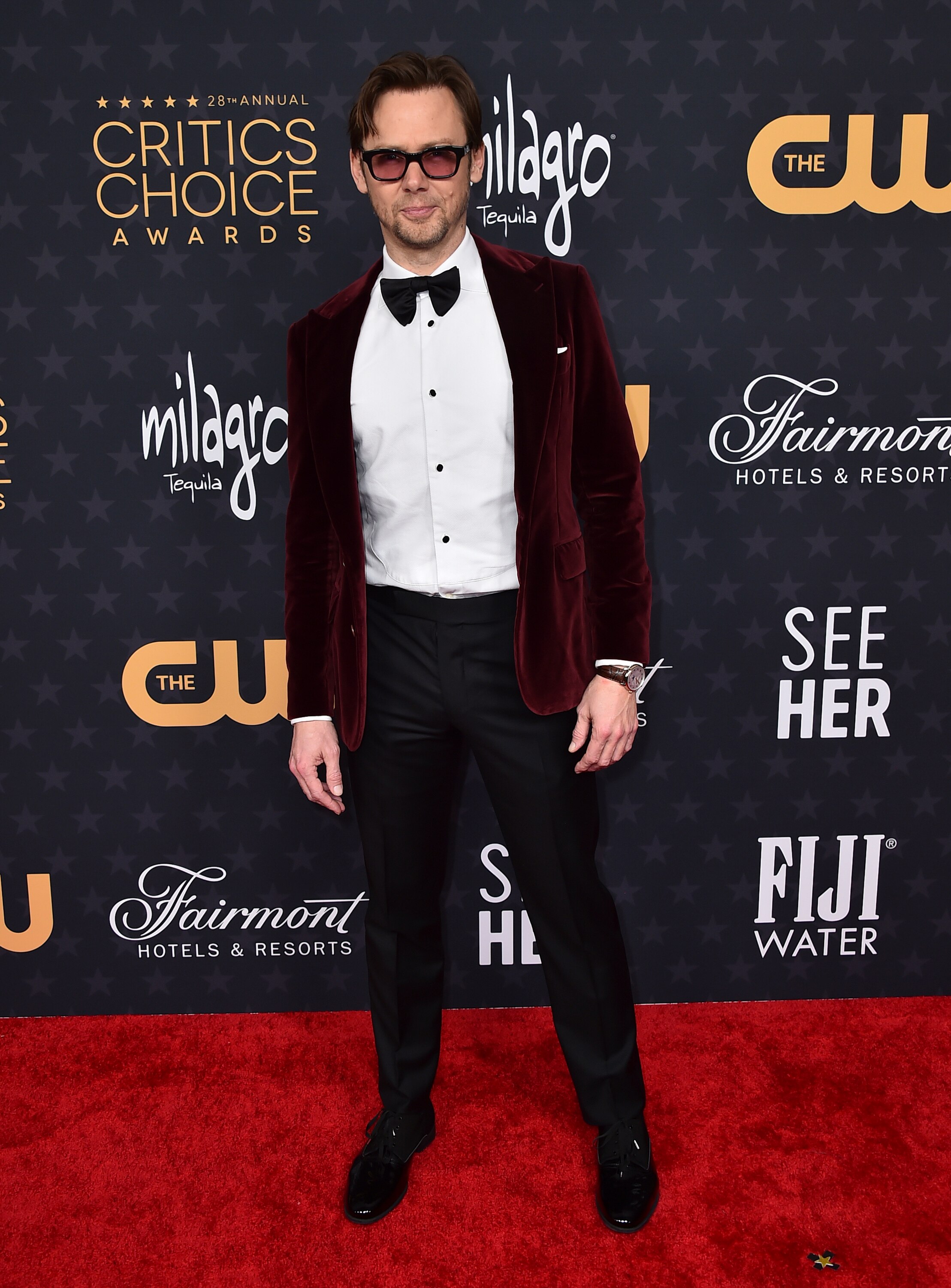 Jimmi Simpson has matched his burgundy suit jacket to his sunglasses with a simple black bow tie. 