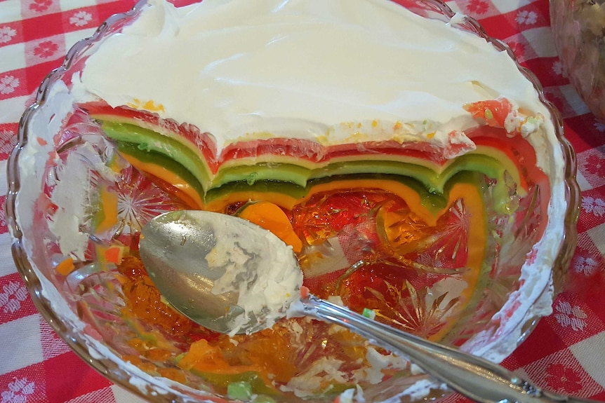 A layered jello salad on a red checked tablecloth.