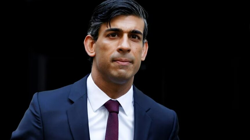 UK Prime Minister Rishi Sunak wearing a navy blue suit and maroon tie