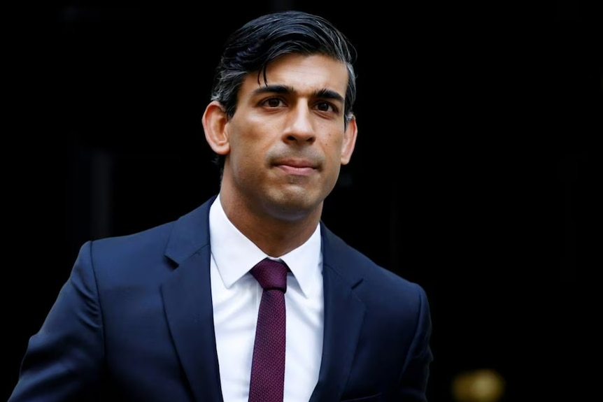 UK Prime Minister Rishi Sunak wearing a navy blue suit and maroon tie