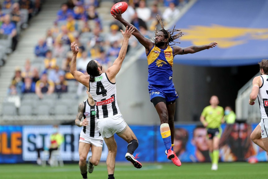 Nic Naitanui leaps higher than Brodie Grundy at a centre bouncedown and wins the tap