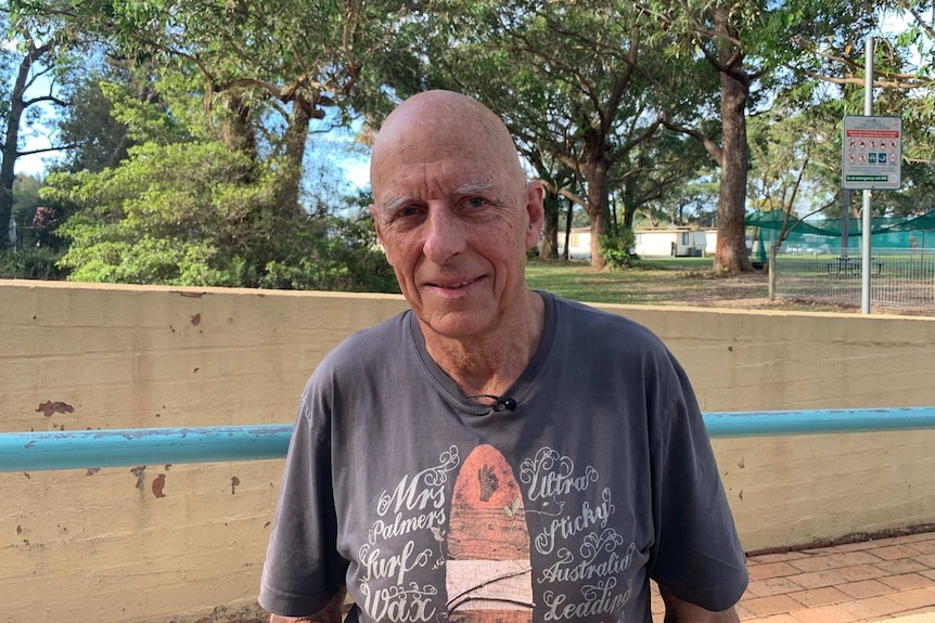 elderly man in a park smiling at camera