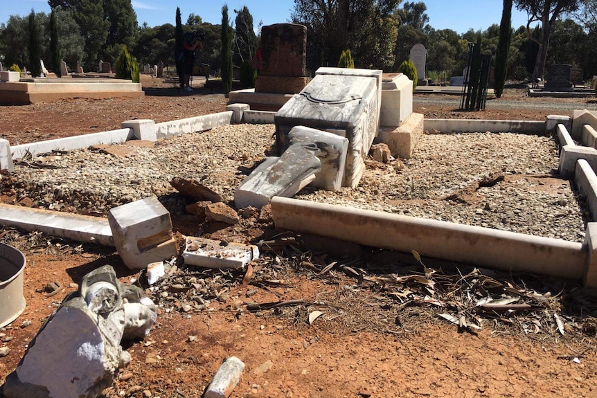 A smashed monument in a cemetery.