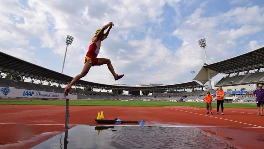 One of the athletes competes in the long-jump event at a stadium