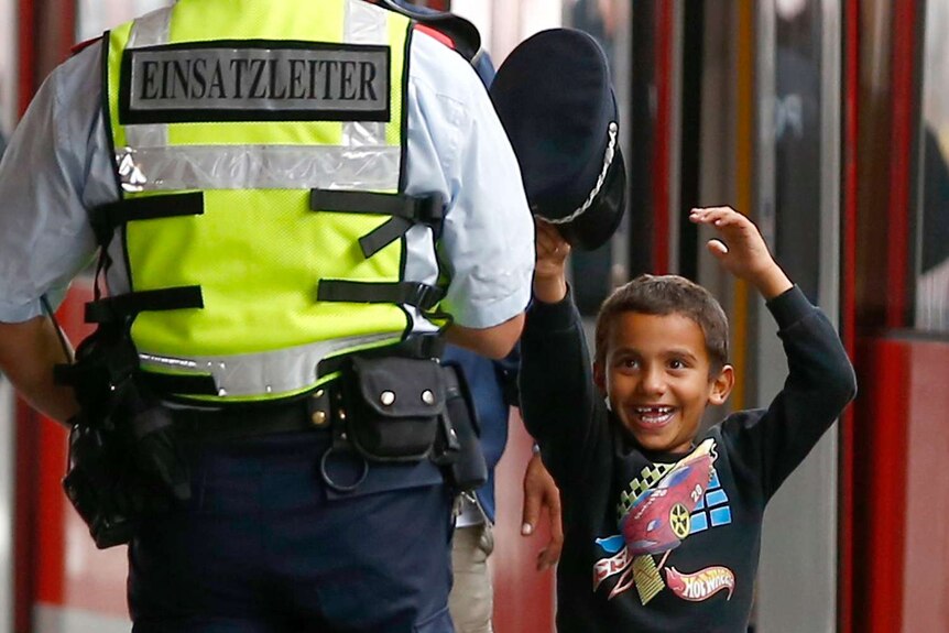 A young asylum seeker boy tries on a Bahn security officer's cap