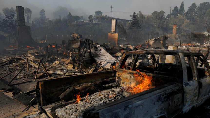 Homes destroyed by wildfire in Ventura next to a  broken truck.