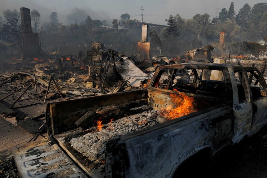 Homes destroyed by wildfire in Ventura next to a  broken truck.