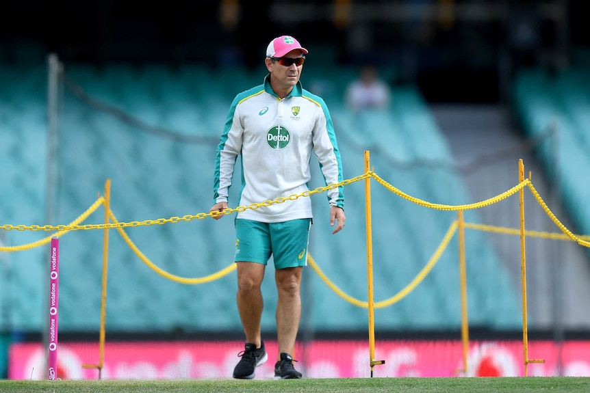 Justin Langer wears green and grey training kit standing surrounded by yellow chains