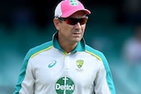 Justin Langer wears green and grey training kit standing surrounded by yellow chains