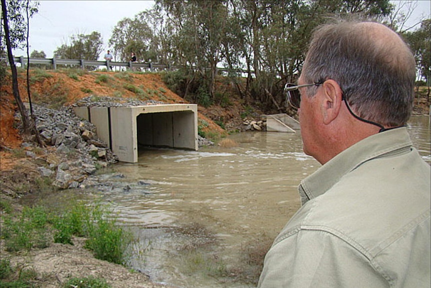 A man watches as water flows out of a regulator into the environment.