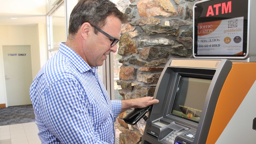 Man in check shirts uses money machine