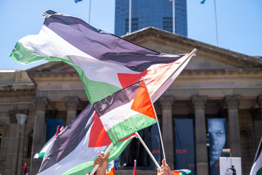 Palestinian flags wave in the air on a sunny day.