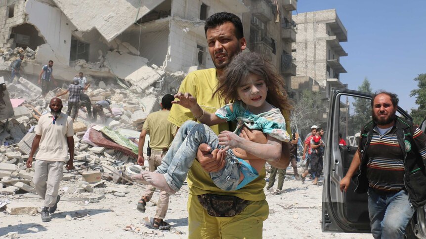 A Syrian man carries a child in the Maadi district of eastern Aleppo after regime aircrafts drop barrel bombs.