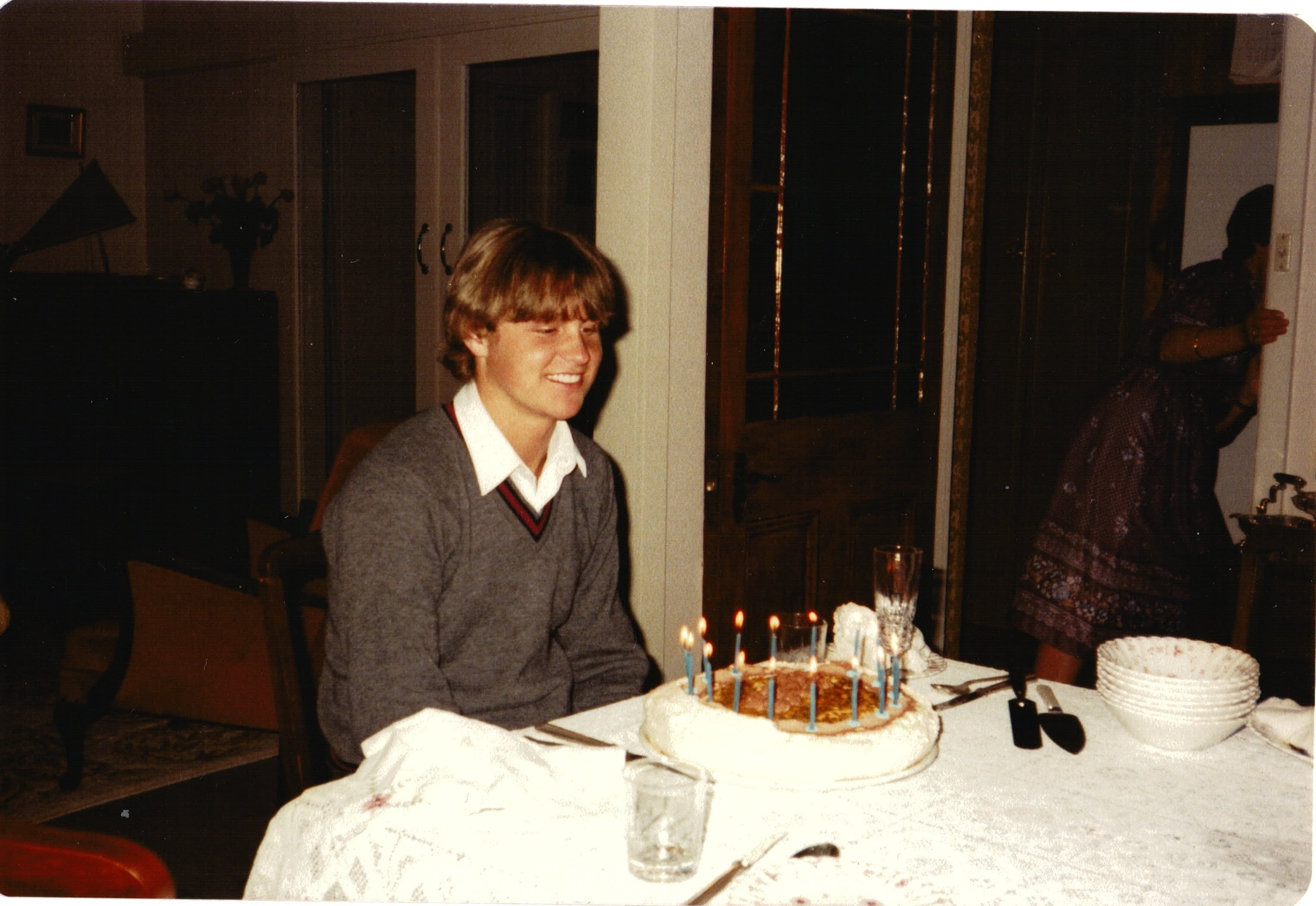 A teenage boy sits at a table with a birthday cake.