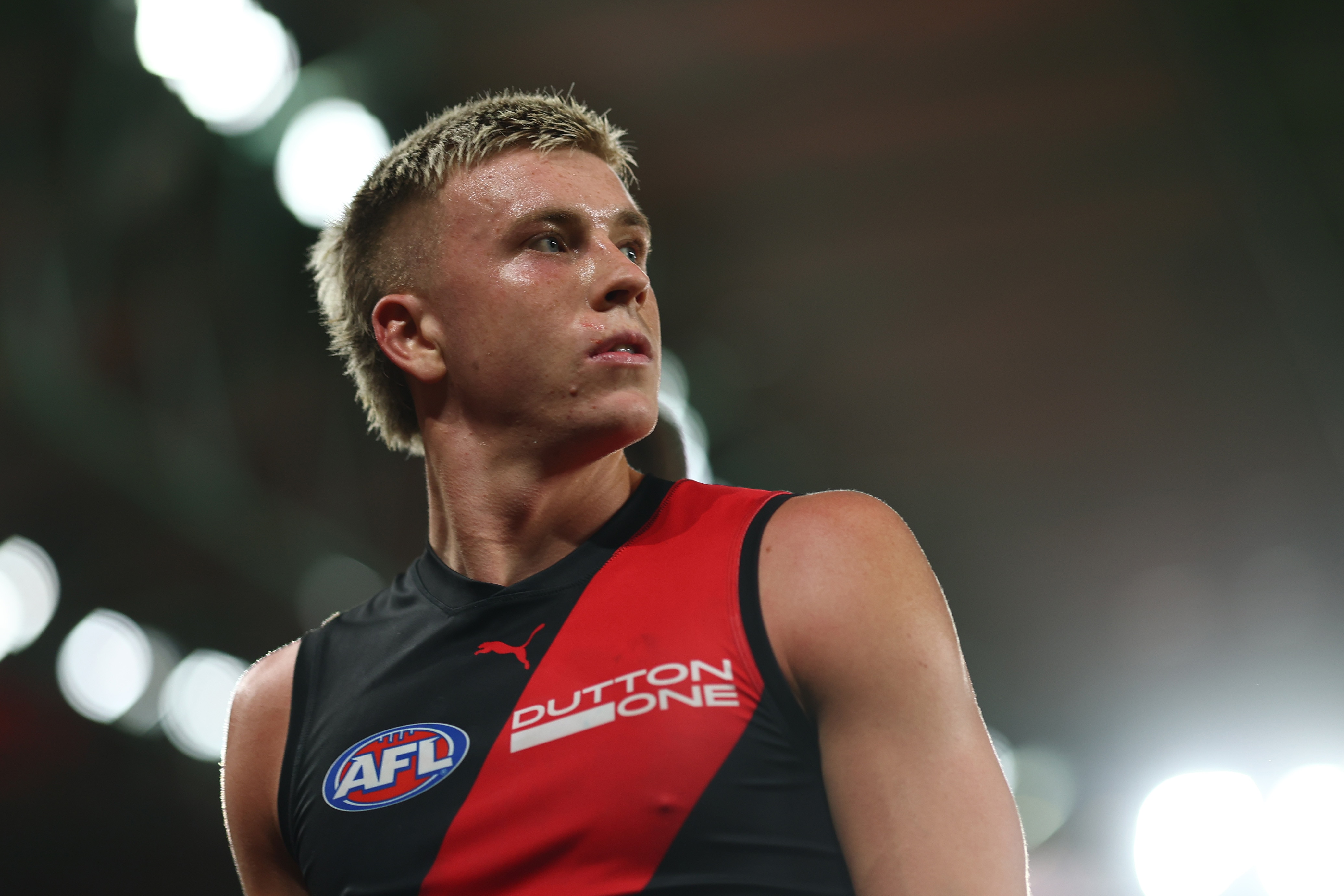 Nate Caddy looks to his left wearing Essendon jersey