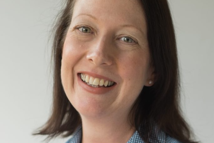 A woman in a business shirt smiling at the camera