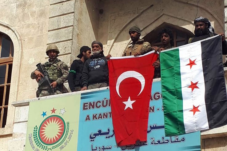 Wide shot of men hoisting flags over a balcony.