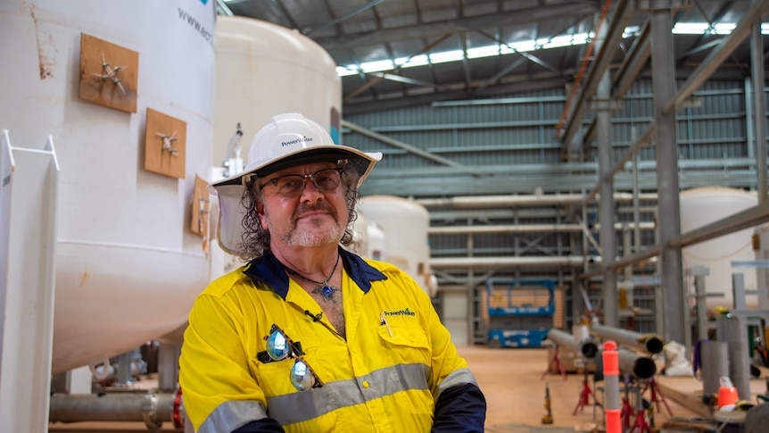 A man stands in a yellow uniform at a PFAS water treatment plant.