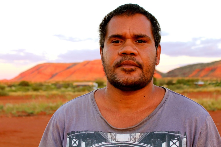 A portrait of 33 year-old David Lans with a large red rocky mountain in the background.