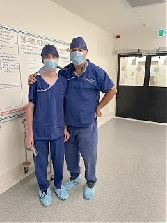 Two people wear blue scrubs in a hospital