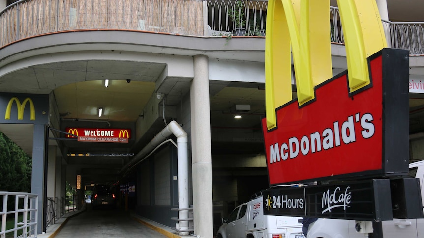 The entrance to a tunnel drive-through to McDonald's, with a sign for the restaurant and McCafe in the foreground.
