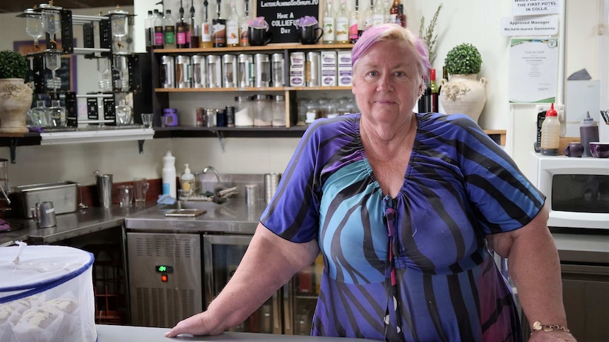 A cafe owner stands behind a counter