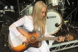 A woman is holding a guitar sitting down