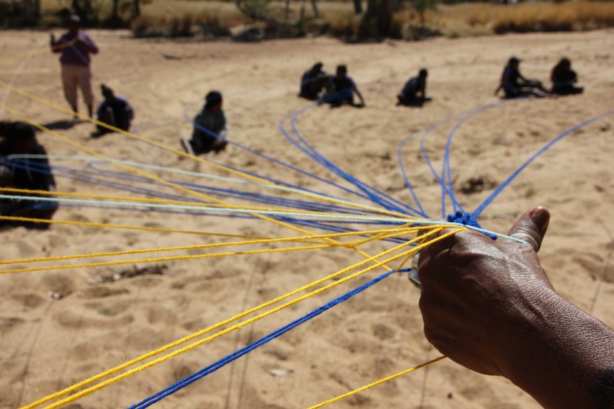 A hand holds strings connecting students