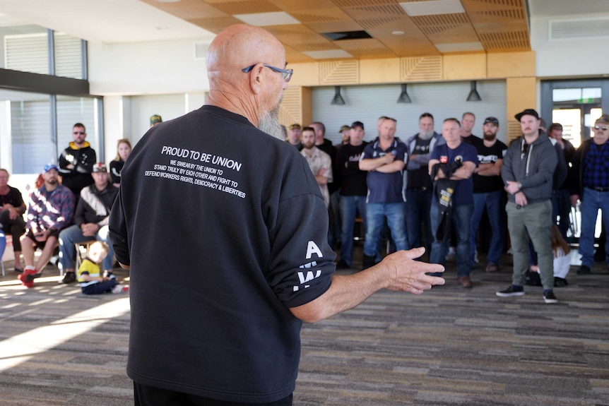 An man with 'proud to be union' on the back of his jumper addresses a group people.