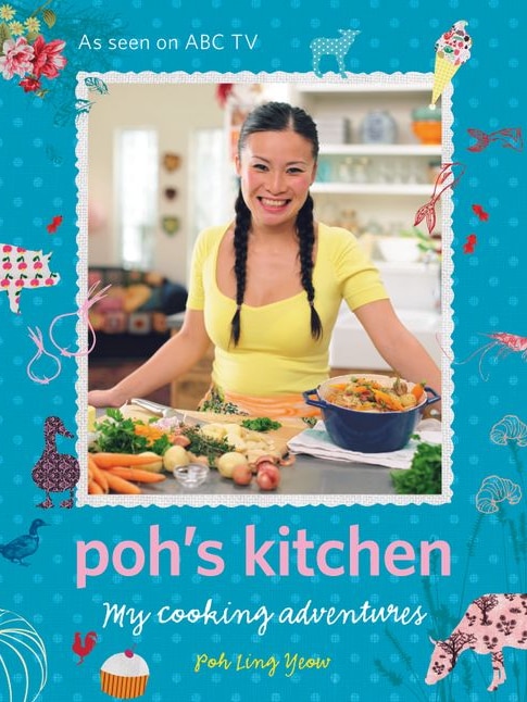 Poh Ling Yeow smiles at the camera while standing behind a bench top full of vegetables.