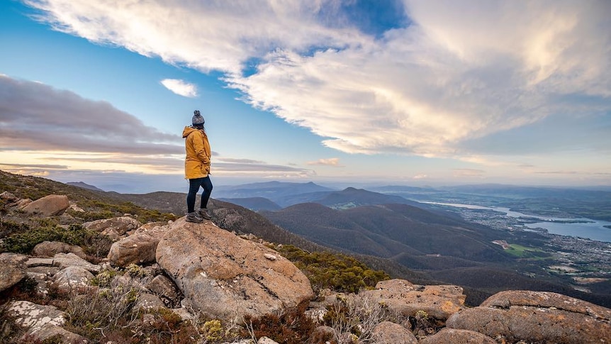 A person stands on the top of Mount Wellington wearing warm clothes.