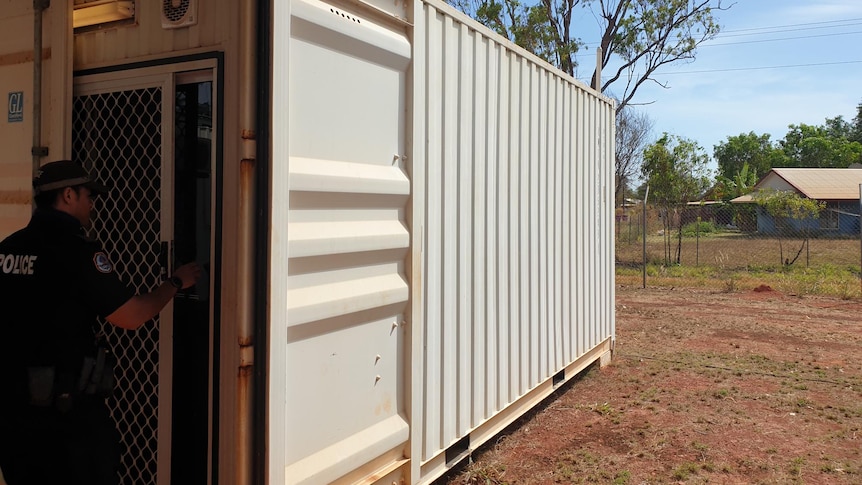 A police officer enters a shipping container.