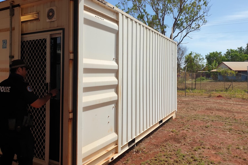 a police officer enters a shipping container