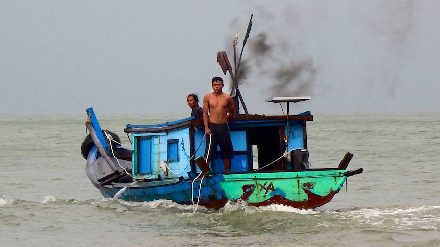 An Indonsian fishing boat with several topless men on board.