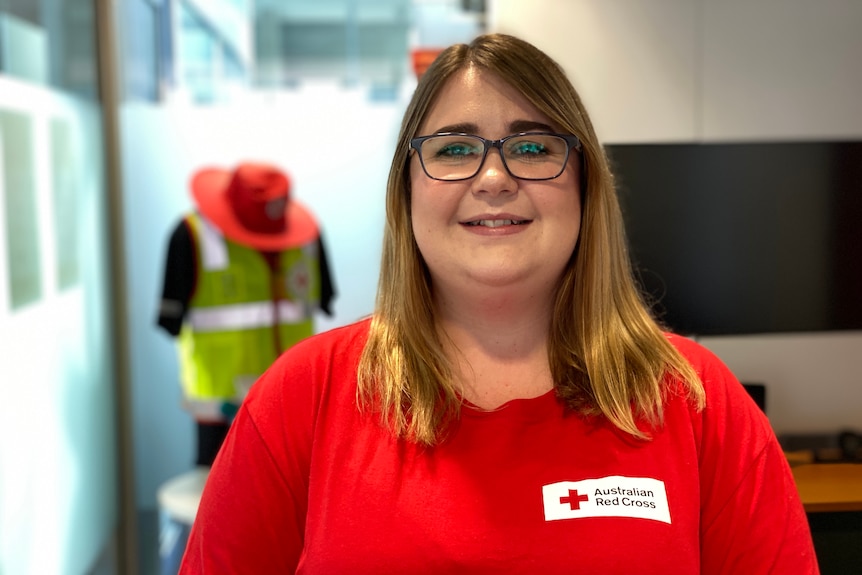 Young woman wearing glasses and wearing red cross t-shirt.