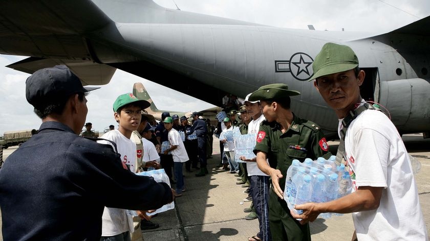 Service members from Burma unload food packages from a US Airforce C-130