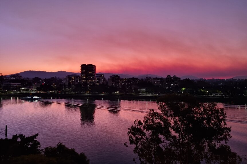 Orangy-purple sunset in West End looking across Brisbane River to Mt Coot-Tha with smoke visible above hills
