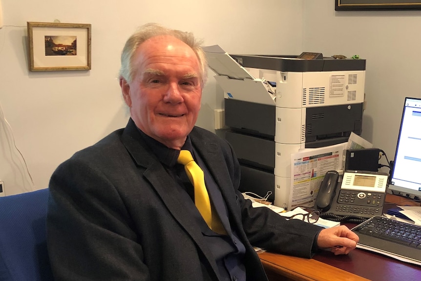 man in three piece suit sits at computer