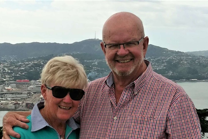 couple standing with arms around each other in front of view of bay