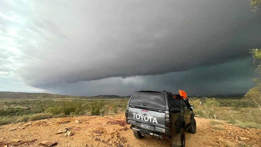 a car in the foreground with large storm cloud overhead