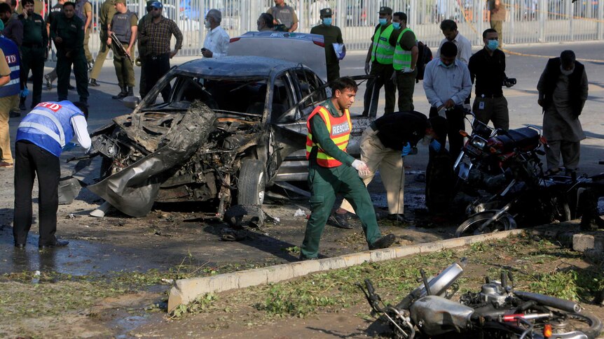 A rescue worker walks among the wreckage of motorbikes and a car.