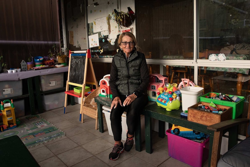 Barb sitting in her home day care and smiling at the camera.