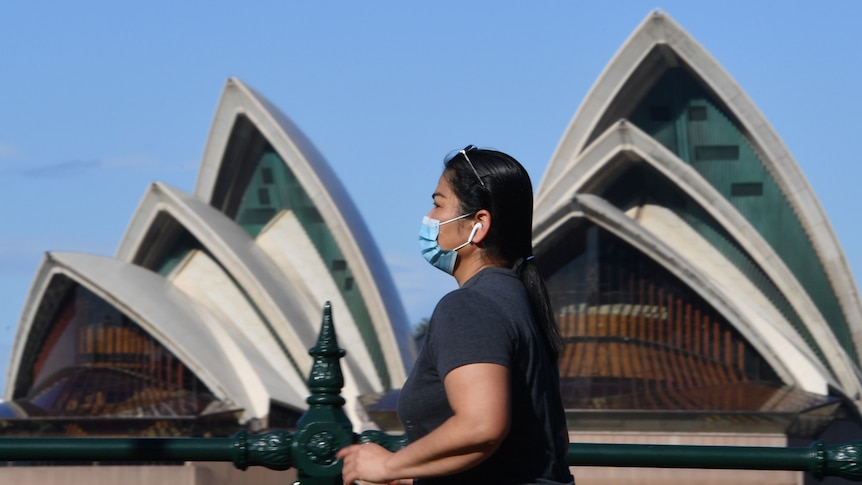 A woman walking past the Opera House.