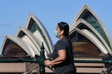 A woman walking past the Opera House.