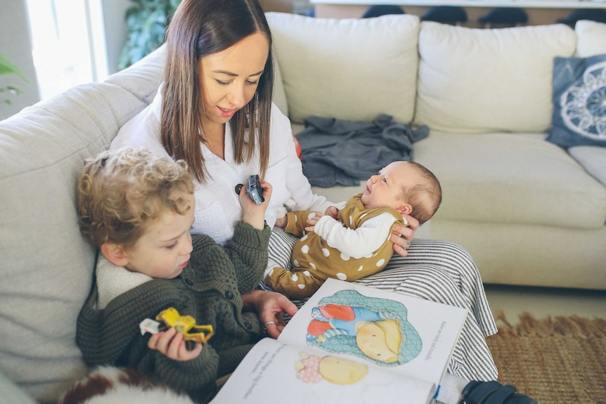 Amy Purling sitting on a couch with her toddler next to her and her baby in her lap