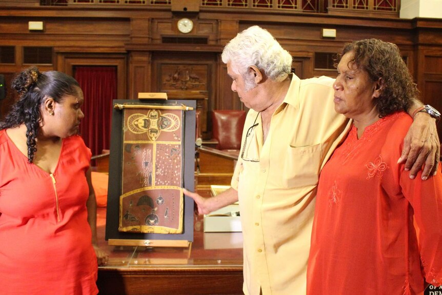 Alfred Bonner with his partner Susan Foster and daughter Remona Bonner with the bark painting depicting the life story of his father Neville Bonner.