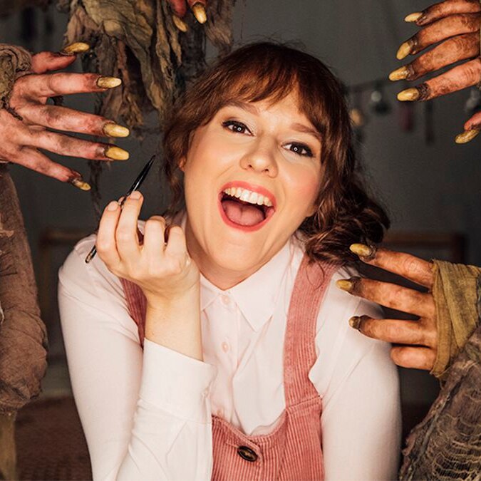 A young white woman applies makeup surrounded by dirty gross hands